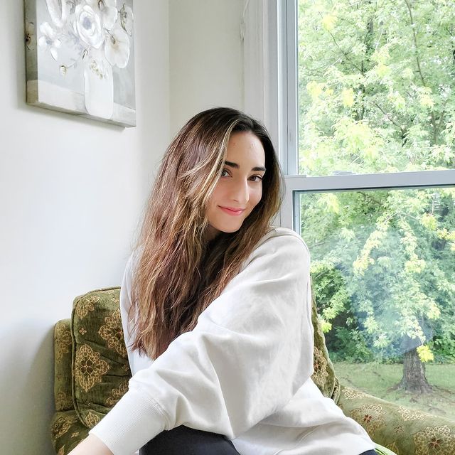 Abigail Shapiro wearing a white sweatshirt and sitting on a chair